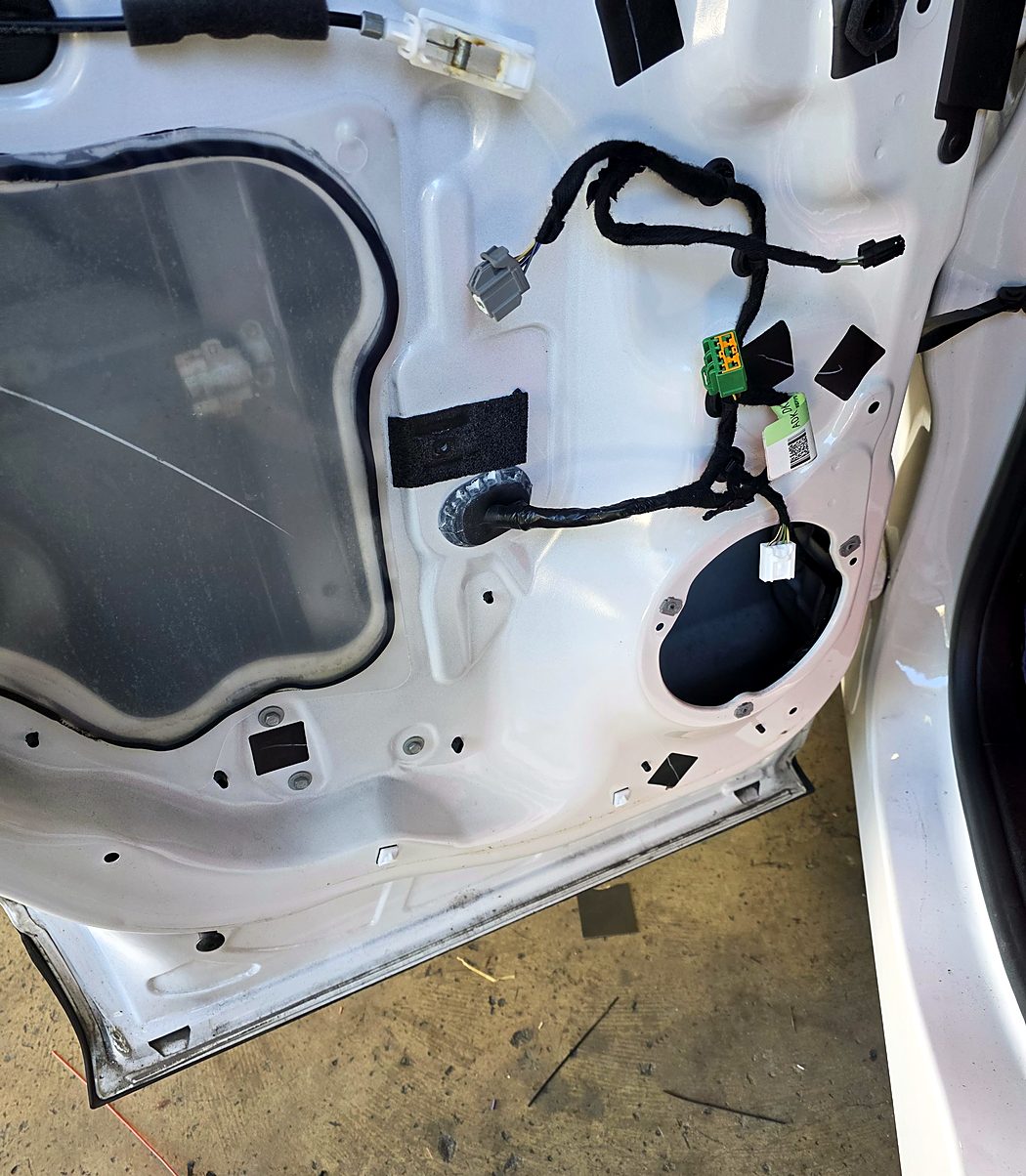 Factory front door speaker removed, leaving the open speaker opening