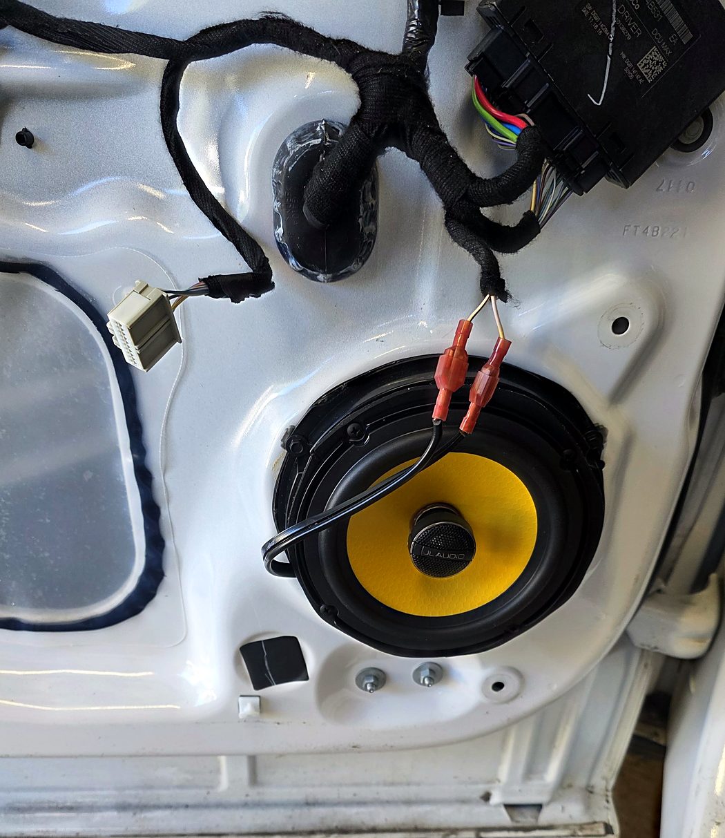 JL Audio C1-650x coaxial speaker with a yellow cone installed in the Ford Edge door