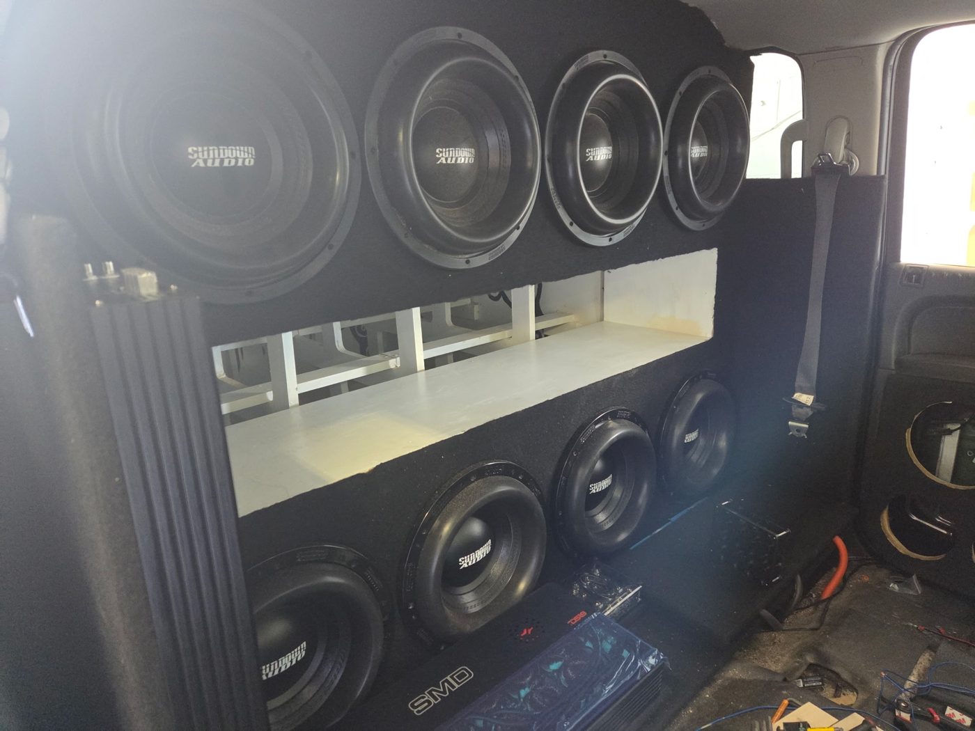 Eight Sundown 12-inch subwoofers mounted in the wall with a white port in the middle