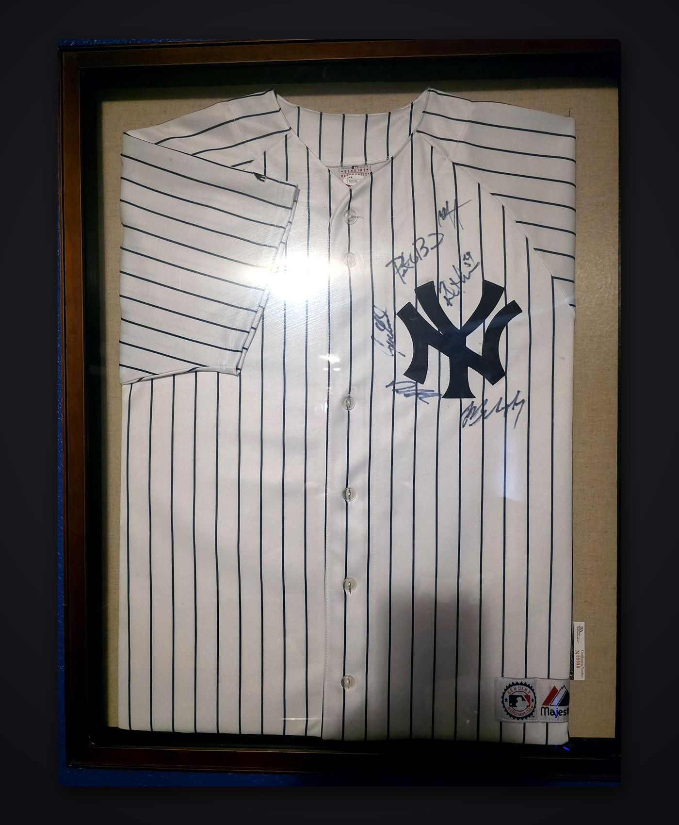 Framed New York Yankees home pinstripe jersey with six signatures around the NY logo